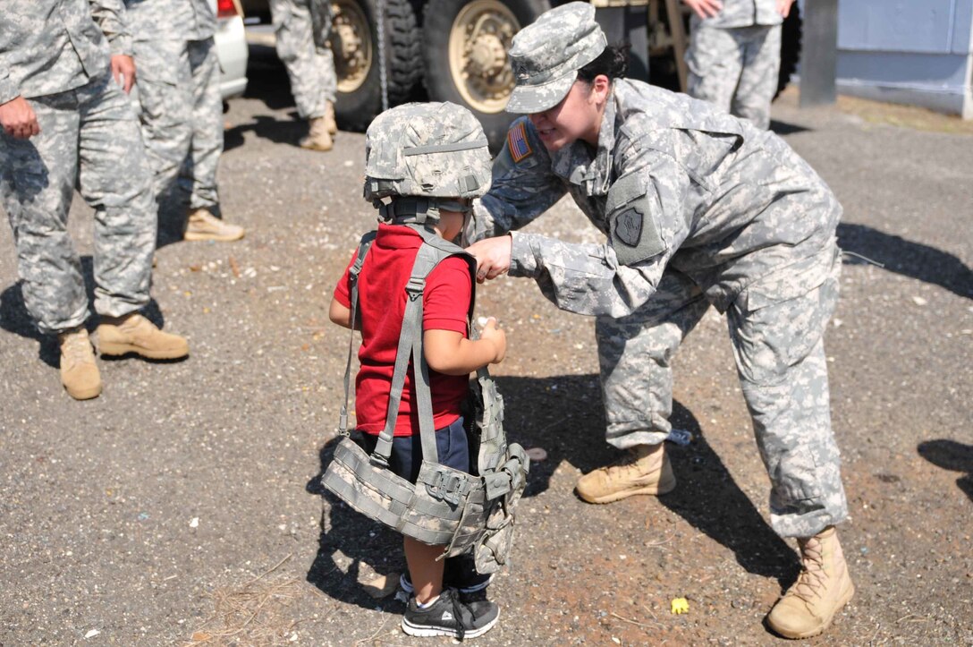 Soldiers of the 613th MP Company participate in Federal Day at El Tuque Head Start, Ponce, Puerto Rico, on Oct. 22.  Children ages 2-5 took turns trying on the Kevlar helmet and load bearing vest before lining up to climb up on the deuce and half truck.