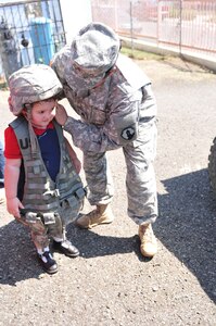 Soldiers of the 613th MP Company participate in Federal Day at El Tuque Head Start, Ponce, Puerto Rico, on Oct. 22.  Children ages 2-5 took turns trying on the Kevlar helmet and load bearing vest before lining up to climb up on the deuce and half truck.