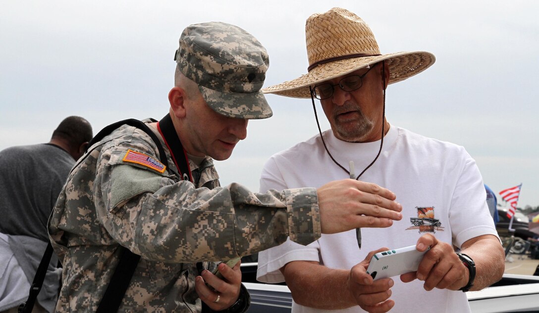 Stan Smith, Vietnam veteran, shows Spc. Thomas Crough, 201st Press Camp Headquarters, Bell, Calif., photos from his time in the Navy at the 14th Annual Wings, Wheels and Rotors Expo at Joint Forces Training Base Los Alamitos, Calif., Oct. 25, 2015. Smith served in the Navy from 1967 to 1970 as a Communication Technician aboard the USS Saint Paul (CA-73). The Wings, Wheels and Rotors Expo, produced by the Los Alamitos Area Chamber of Commerce, features hundreds of hot rods and exotic cars, helicopters, airplanes and vintage warplanes on display combined with local vendors, great food and exhibits from law enforcement agencies and the military.