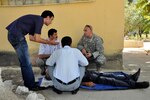 Army Staff Sgt. Nicholas Bruce, training noncommissioned officer, Medical Command, Massachusetts National Guard, and the non-commissioned officer of the medical exercise in Tajikistan, talks with the first responders as they work through a training lane, Sept. 22, 2011.