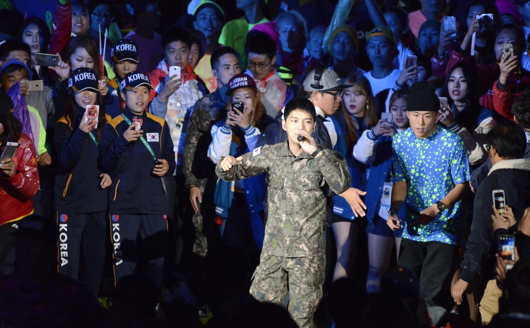 Korean athletes snap photos of pop star Kim Jaejoong as he sings Arirang in the center of the stadium during the closing ceremony for the CISM World Games Oct. 11, 2015, in MunGyeong, South Korea.