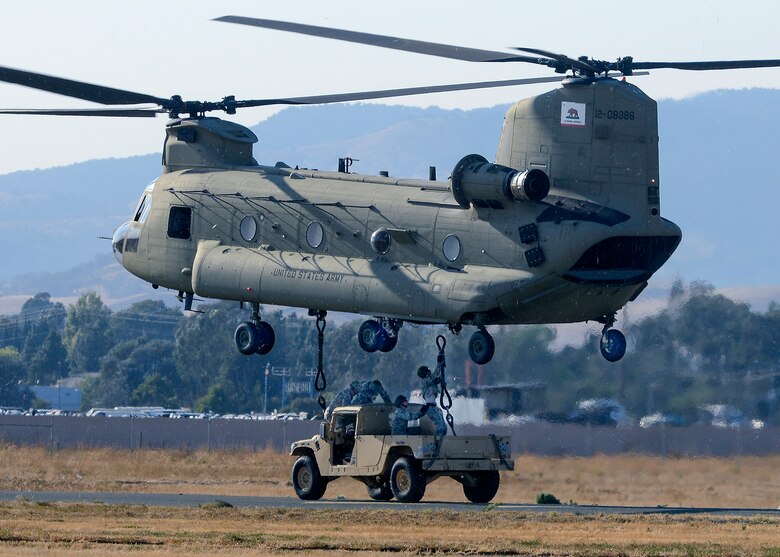 Airmen from the 60th Aerial Port Squadron and members of the Army National Guard's 49th Police Brigade practice loading and sling loading vehicles on a CH-47 Chinook cargo helicopter Oct. 14, 2015, at Travis Air Force Base, Calif. The units also practiced nighttime operations in total darkness with the aid of night vision goggles. (U.S. Air Force photo/T.C. Perkins Jr.) 