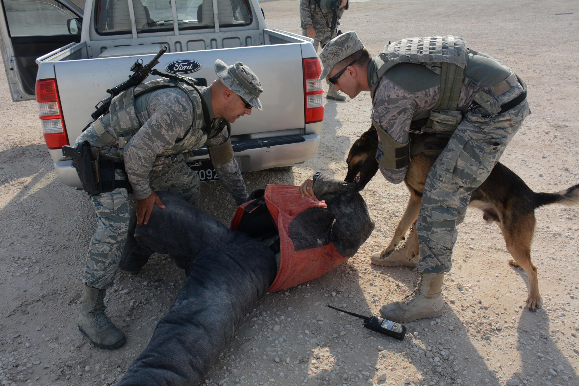 A military working dog and two security forces airmen assigned to the 379th Expeditionary Security Forces Squadron, take a suspect into custody during an interagency training exercise at Al Udeid Air Base, Qatar Oct. 27. The exercise featured professionals from three 379th Air Expeditionary Wing units including explosive ordnance technicians, security forces patrolmen and firefighters. (U.S. Air Force photo by Tech. Sgt. James Hodgman)
