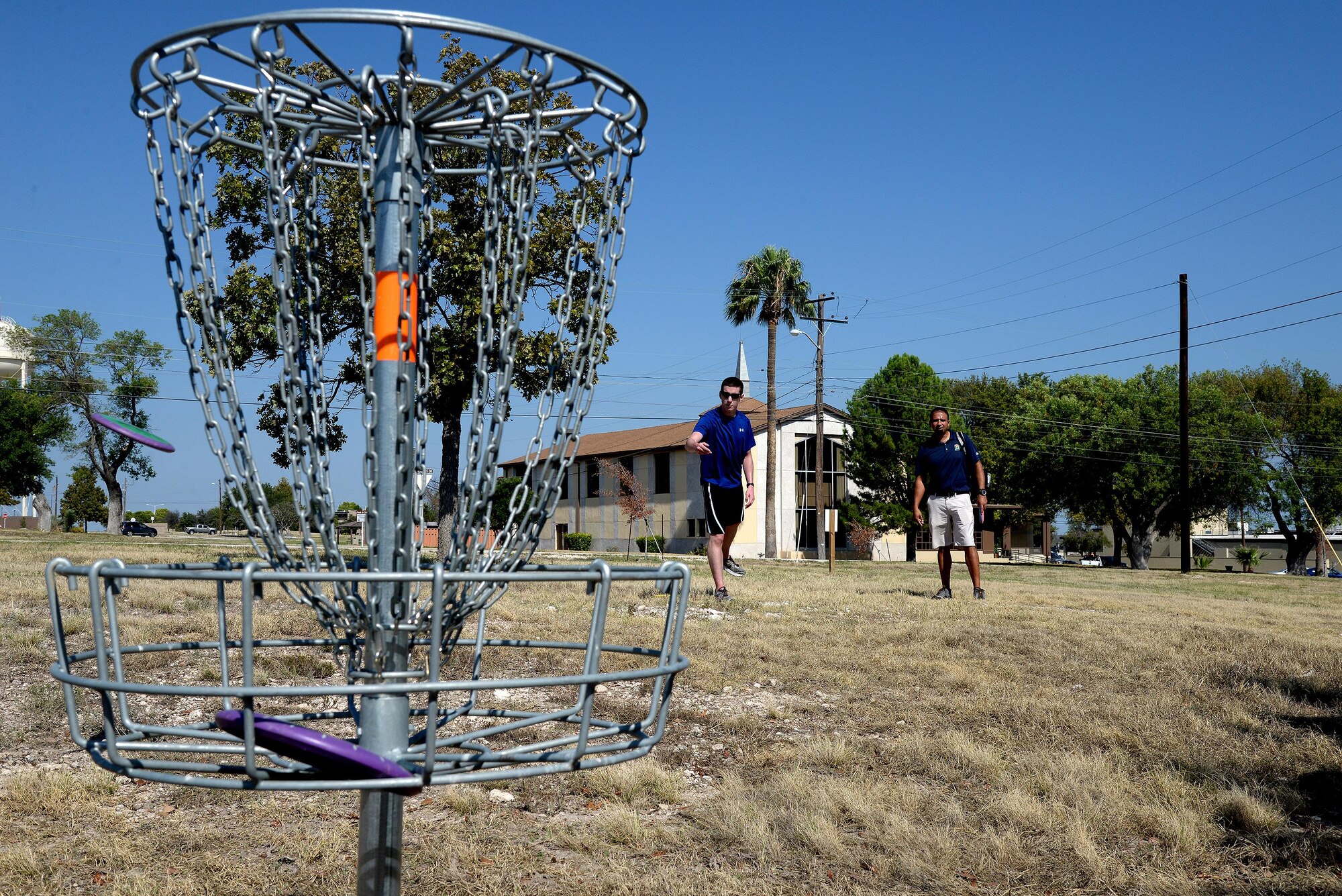 Second Lt. Matt Kellen, left, 47th Student Sqaudron student pilot recieves disc golf instruction from Fernando Brown, 47th Force Support Squadron Outdoor Recreation manager at the Dragon Lady Links disc golf course on Laughlin Air Force Base, Texas, Oct. 14, 2015. Dragon Lady Links is free to play , and the driver, mid-range, and putter disc can be rented at Outdoor Recreation for $2 a day. (U.S. Air Force photo by Airman 1st Class Brandon May)(Released)