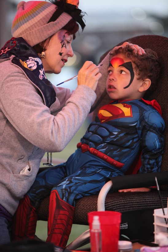 Robin Ware paints the face of 4-year-old Cameron during the Trunk-or-Treat event at Marine Corps Air Station Cherry Point, N.C., Oct. 26, 2015. The event was hosted by Marine Wing Headquarters Squadron 2 and Marine Aircraft Group 14 family readiness officers to encourage families to come together in a safe and fun environment to trick-or-treat. During the event, service members, spouses and family members were able to play games, watch Halloween movies and trick-or-treat. (U.S. Marine Corps photo by Cpl. U. B. Roberts/Released.)