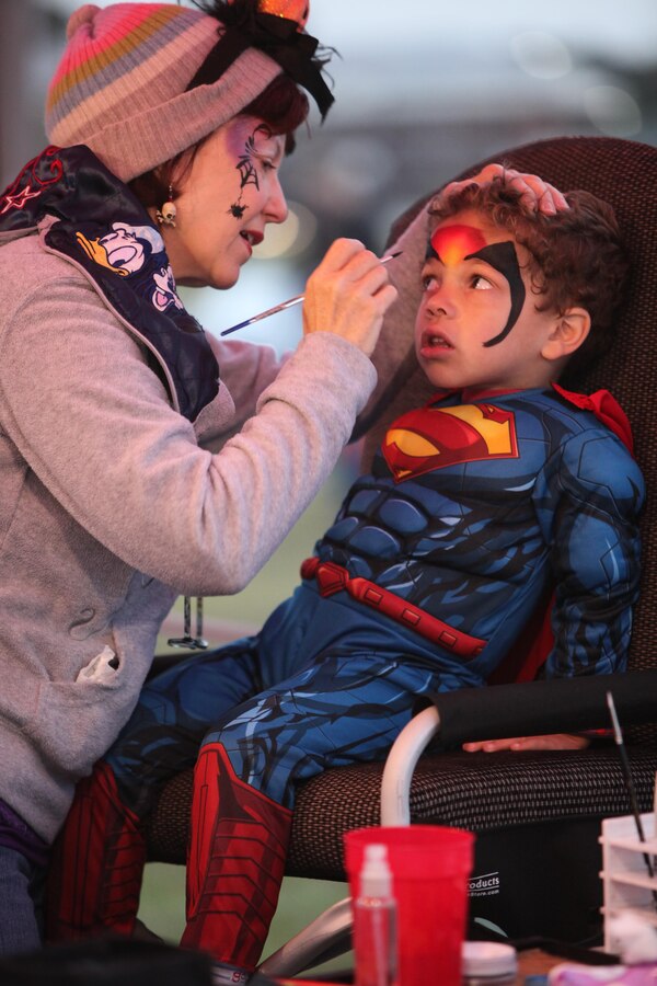 Robin Ware paints the face of 4-year-old Cameron during the Trunk-or-Treat event at Marine Corps Air Station Cherry Point, N.C., Oct. 26, 2015. The event was hosted by Marine Wing Headquarters Squadron 2 and Marine Aircraft Group 14 family readiness officers to encourage families to come together in a safe and fun environment to trick-or-treat. During the event, service members, spouses and family members were able to play games, watch Halloween movies and trick-or-treat. (U.S. Marine Corps photo by Cpl. U. B. Roberts/Released.)