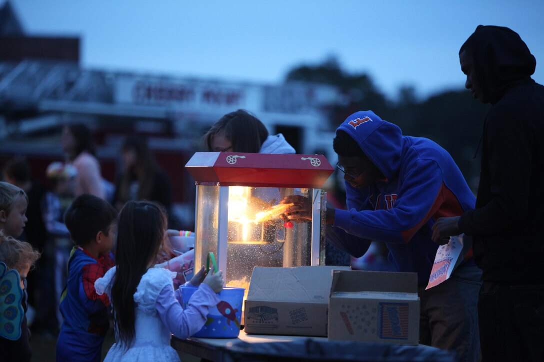 Volunteers with Marine Wing Headquarters Squadron 2 and Marine Aircraft Group 14 serve popcorn to children during the 3rd Annual Trunk-or-Treat at Marine Corps Air Station Cherry Point, N.C., Oct. 26, 2015. The event was hosted by Marine Wing Headquarters Squadron 2 and Marine Aircraft Group 14 family readiness officers to encourage families to come together in a safe and fun environment to trick-or-treat. During the event, service members, spouses and family members played games, watched Halloween movies and went trick-or-treating. (U.S. Marine Corps photo by Cpl. U. B. Roberts/Released.)