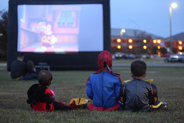 Service members, spouses and families watch a movie during the 3rd Annual Trunk-or-Treat at Marine Corps Air Station Cherry Point, N.C., Oct. 26, 2015. Families and spouses watched Halloween themed movies like “The Ghost of Lord Farquaad” and “Alvin and the Chipmunks: Halloween collection.” The event was hosted by Marine Wing Headquarters Squadron 2 and Marine Aircraft Group 14 to allow family members to get together and celebrate Halloween in a safe and fun environment.   (U.S. Marine Corps photo by Cpl. U. B. Roberts/Released.)
