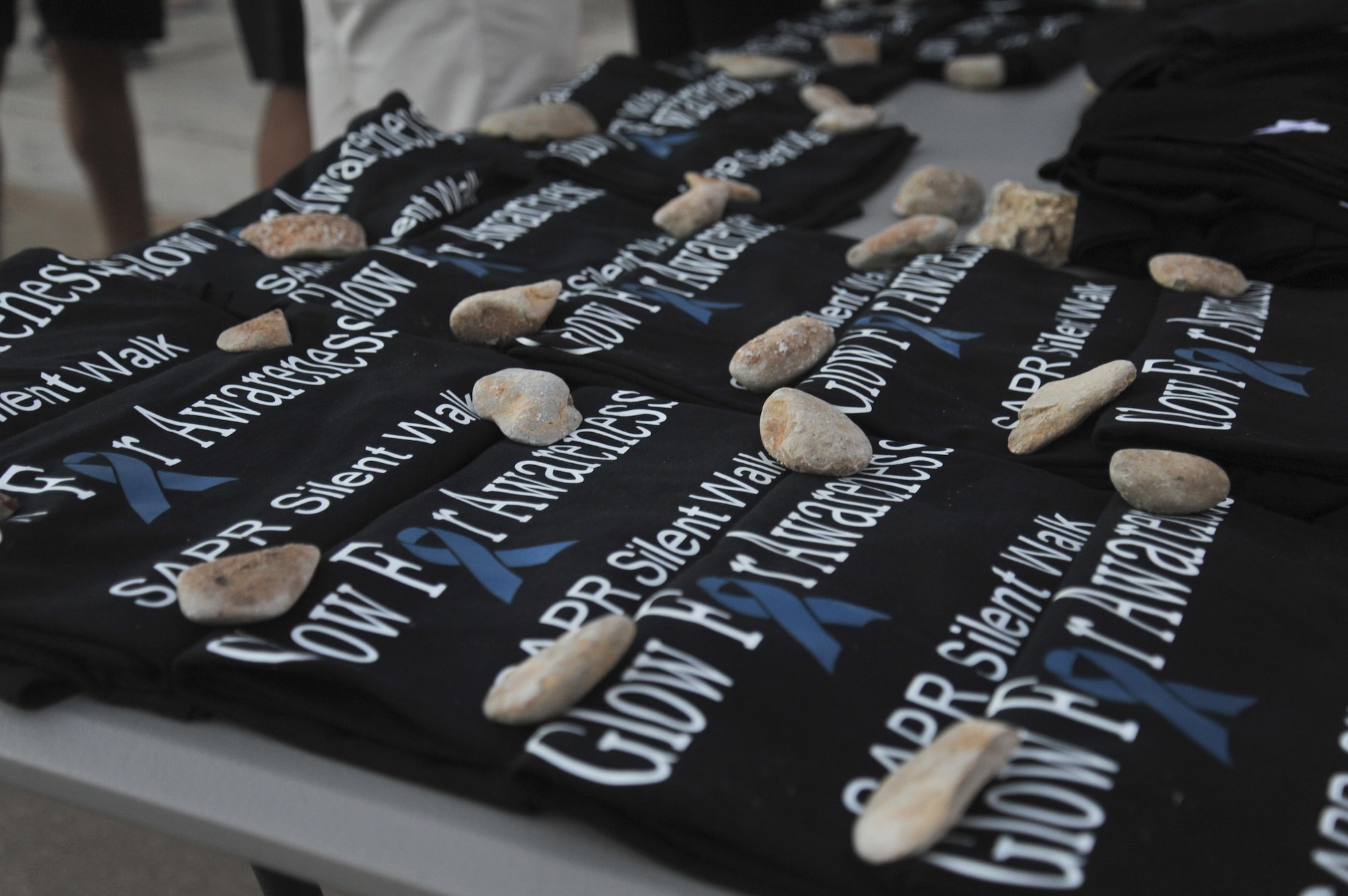T-shirts rest on a table for the participants in the Sexual Assault Prevention and Response program’s Silent Glow Walk at Goodfellow Air Force Base, Texas, Oct. 27, 2015. Sexual Assault Response Coordinators handed out the shirts and encouraged participants to wear them during the Walk. (U.S. Air Force photo by Airman Chase Sousa/Released)