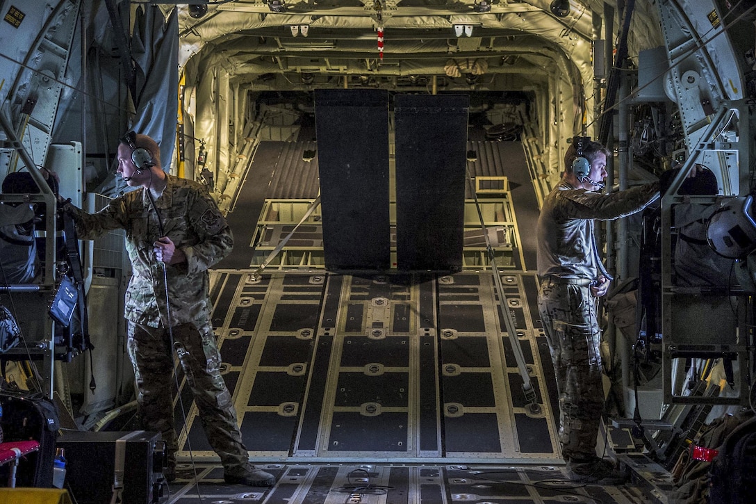 Two U.S. airmen look out the windows of a C-130J Hercules during rescue and refueling training near Beja Air Base, Portugal, Oct. 23, 2015. The training supported Trident Juncture 2015, which is the largest NATO exercise conducted in the past 20 years, with more than 35,000 troops from over 30 NATO member nations and partners participating. The airmen are assigned to the 71st Rescue Squadron. U.S. Air Force photo by Airman 1st Class Luke Kitterman
