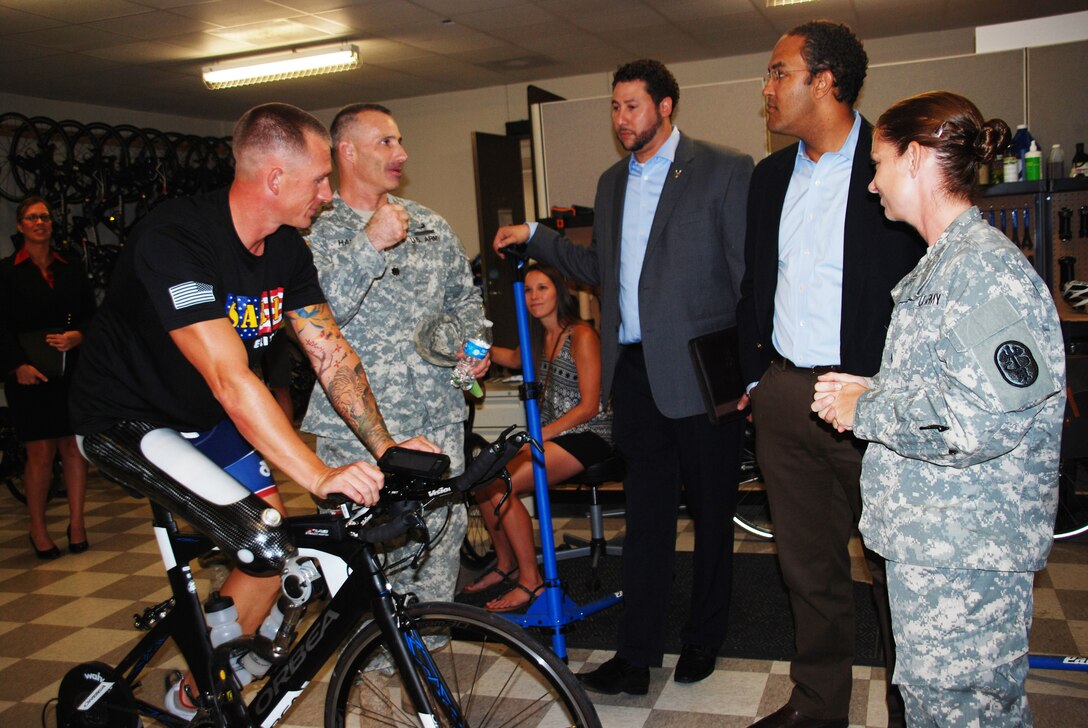 Army Lt. Col. Michael Harper, commander of Warrior Transition Battalion, speaks to U.S. Rep. Will Hurd during adaptive reconditioning demonstrations as Staff Sgt. Allen Armstrong, far left, Jon Arnold, center, and Sgt. 1st Class Samantha Goldensten, far right, the battalion’s Soldier Adaptive and Reconditioning Program noncommissioned officer in charge, look on during a tour of the battalion’s facilities, Sept. 15, 2015. U.S. Army photo by Maria Gallegos