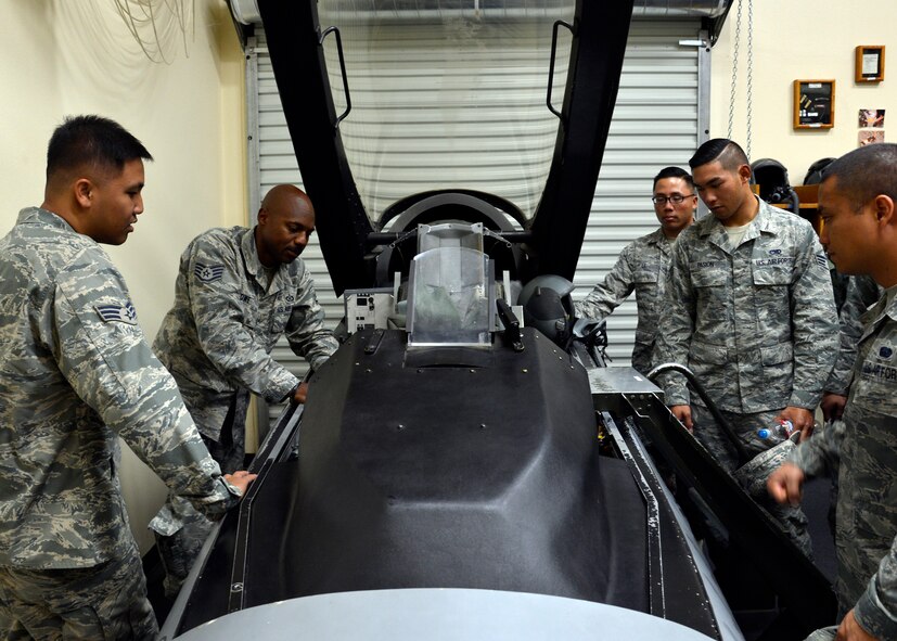 Staff Sgt. Brandon Rowe (far left), 56th Operations Support Squadron aircrew flight equipment training NCO in charge, show the Airman Leadership Class 15-7 the inside of   an F-16 Fighting Flacon cockpit training module during their tour of the 62nd Fighter Squadron at Luke Air Force Base, Ariz., Oct. 28, 2015. The 62nd FS took the ALS students on a tour across their unit and showed them what a day in the life of a fighter pilot is like. (U.S. Air Force photo by Senior Airman Devante Williams) 