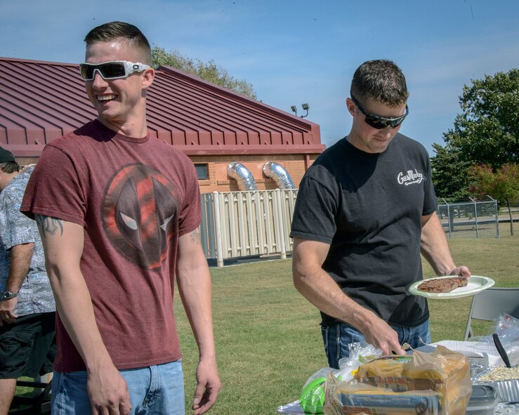 Senior Airman Allan Poston (left) enjoys waiting for 71st Security Forces Squadron commander Capt. Christopher Jackson to finish making the junior Airman a plate of food at Vance Air Force Base, Oklahoma, Oct. 10. As per Rocky Mountain Dawgs Project tradition, the highest-ranking troop in attendance serves the most junior troop to kick-off their signature barbecues. The group was on base to thank 71st SFS military working dog handlers and their families for their selfless service. (U.S. Air Force photo/ David Poe)