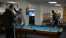Airmen play a game of pool while others play ping pong Oct. 28, 2015 in the Higher Grounds Airmen Ministry Center, Bldg. 248, on F.E. Warren Air Force Base, Wyo. The center aims to create a local community for Airmen to go to and relax each night during the week. (U.S. Air Force photo by Senior Airman Brandon Valle)