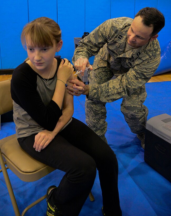 Capt. Marc Dunham, 51st Medical Operations Squadron multi-service inpatient unit, gives a child a flu shot during a simulated non-combatant evacuation operation simulation on Osan Air Base, Republic of Korea, Oct. 24, 2015. During the NEO line simulation, Osan dependents were able to go over evacuation plans, financial briefings and family accommodations. To make it easier for families, volunteers from the 51st Medical Group also administered flu shots and mists for the season. (U.S. Air Force photo/Senior Airman Kristin High)