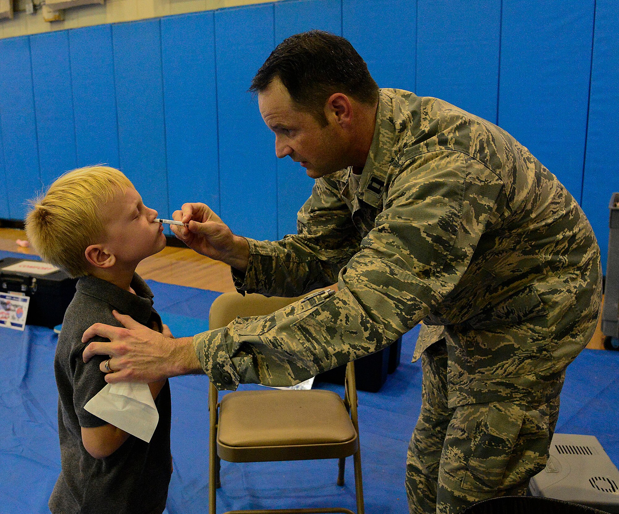 Capt. Marc Dunham, 51st Medical Operations Squadron multi-service inpatient unit, gives a child a nasal flu mist during a simulated non-combatant evacuation operation simulation on Osan Air Base, Republic of Korea, Oct. 24, 2015. During the NEO line simulation, Osan dependents were able to go over evacuation plans, financial briefings and family accommodations. To make it easier for families, volunteers from the 51st Medical Group also administered flu shots and mists for the season. The nasal mist is recommended for healthy individuals ages two through 49. (U.S. Air Force photo/Senior Airman Kristin High)