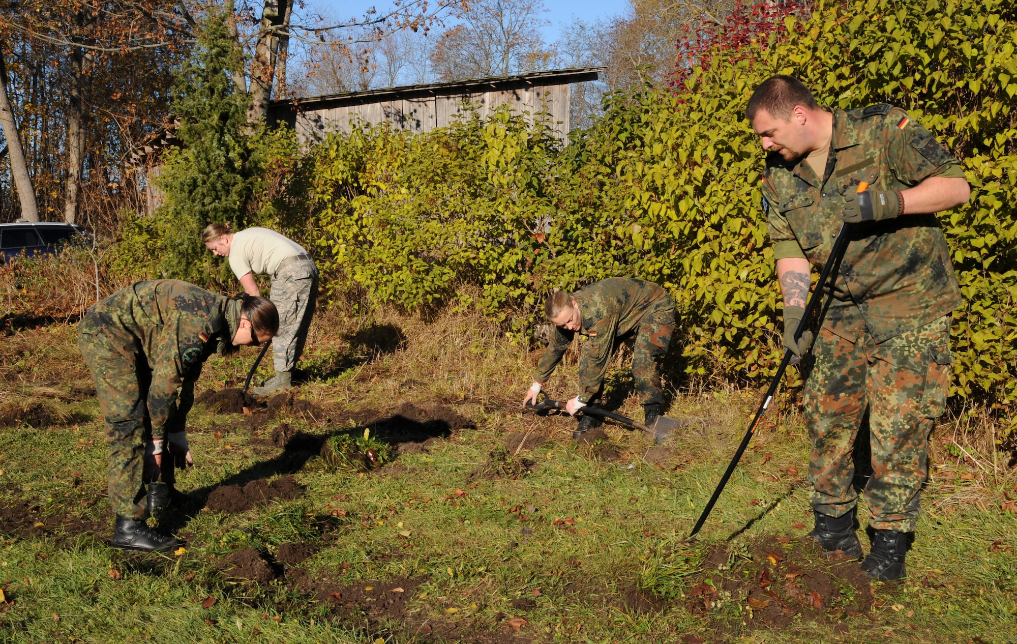 German Air Force airmen and U.S. Air Force Airmen clean up the running path at Vasalemma School Stadium in Amari, Estonia, Oct. 24, 2015. About 100 volunteers helped the school clean up the recess area and build different obstacles for the students. (U.S. Air Force photo by Andrea Jenkins/Released)