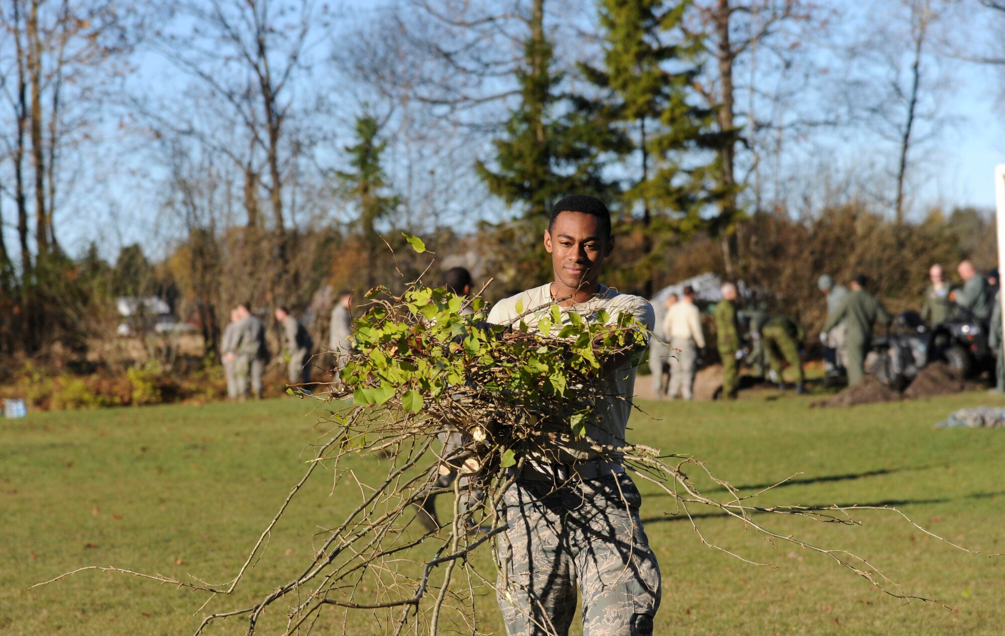 U.S. Air Force Senior Airman Lee Morris, 74th Expeditionary Fighter Squadron traffic management office, carries away yard refuse at Vasalemma School Stadium in Amari, Estonia, Oct. 24, 2015. About 100 U.S., German and Estonian volunteers helped the school clean up the recess area and build different obstacles for the students. (U.S. Air Force photo by Andrea Jenkins/Released)