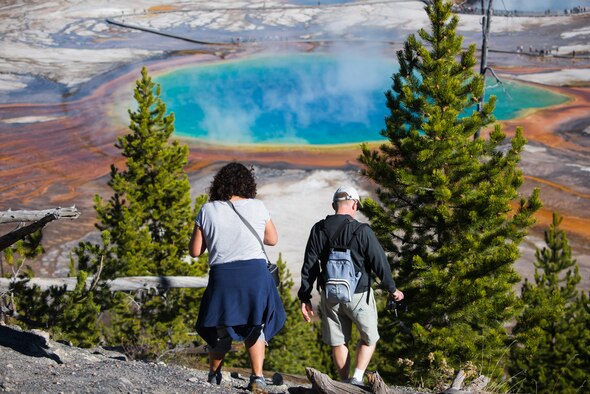 A French couple descends a hill near the Fairy Falls Trailhead after enjoying the view of Grand Prismatic Spring at Yellowstone National Park, Wyoming Oct. 10, 2015. The spring is the third largest in the world and owes its vibrant array of colors to heat-loving bacteria residing in its warm water. (U.S. Air Force photo by Airman 1st Class Connor J. Marth)