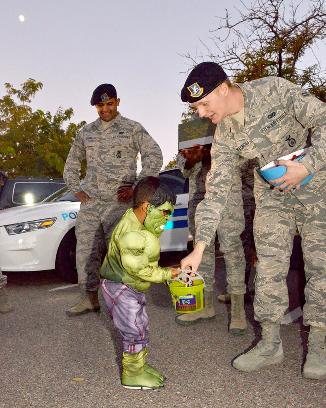 Isaac Key, dressed as the Hulk, gets candy from Airman First Class Kelton Spagnoli as Senior Airman Jeremy Cossio looks on Oct. 23 at Bootastic. The annual Halloween event, sponsored by the Youth Center, provided a free night of games, prizes, safe trick-or-
treating and other fun events for people of all ages. (Photo by Jamie Burnett)