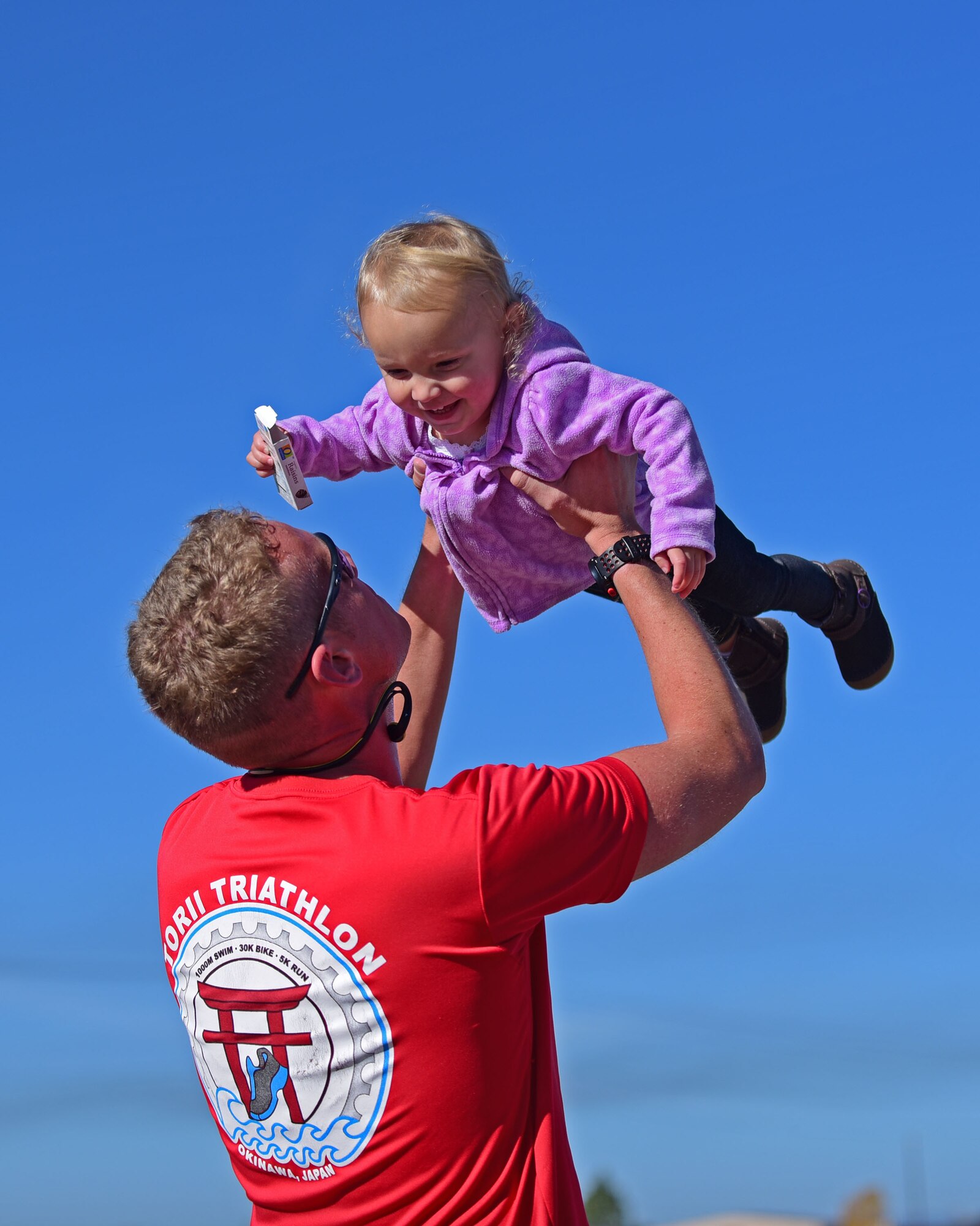 Second Lt. Corey Hayes, 28th Force Support Squadron readiness officer in charge, celebrates with his daughter after finishing first in the Fall Triathlon at Ellsworth Air Force Base S.D., Oct. 17, 2015. The Bellamy Fitness Center hosted the triathlon to promote physical fitness and friendly competition. (U.S. Air Force photo by Airman 1st Class James L. Miller/Released)