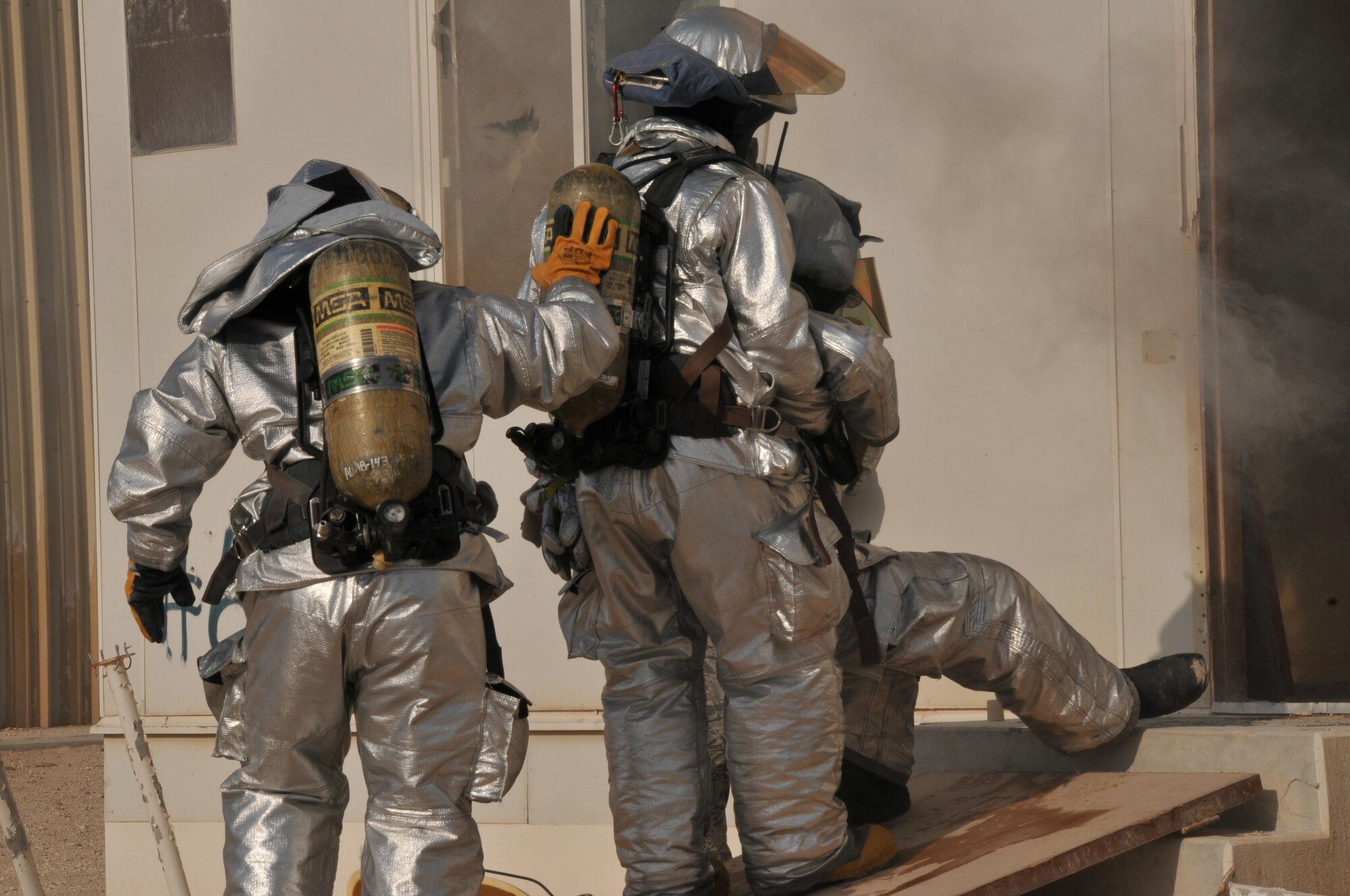 379th Expeditionary Civil Engineer Squadron firefighters arrive at the scene of a simulated burning building during an interagency exercise at Al Udeid Air Base, Qatar Oct. 27. During the exercise, a firefighter stepped on an explosive device to simulate firefighter emergency procedures. Two firefighters escorted the injured firman out of the building and carried him to safety. (U.S. Air Force photo by Tech. Sgt. Terrica Y. Jones/Released)