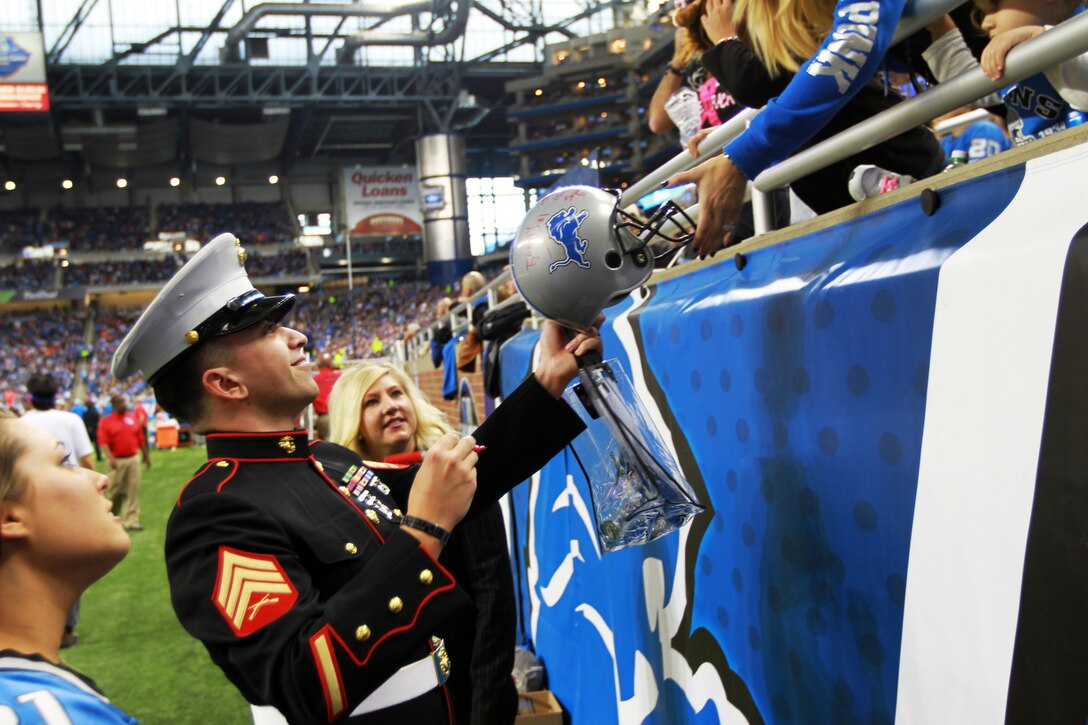 U.S. Marine Sgt. Benjamin J. Annarino signs a fan’s helmet during a Detroit Lions football game Oct. 20, 2015, at Ford Field in Detroit. Annarino was honored as the game’s Hometown Hero during a break in play in the third quarter. Annarino  is a canvassing recruiter for Recruiting Station Detroit and a Livonia, Michigan, native. (U.S. Marine Corps photo by Sgt. J. R. Heins/ Released)
