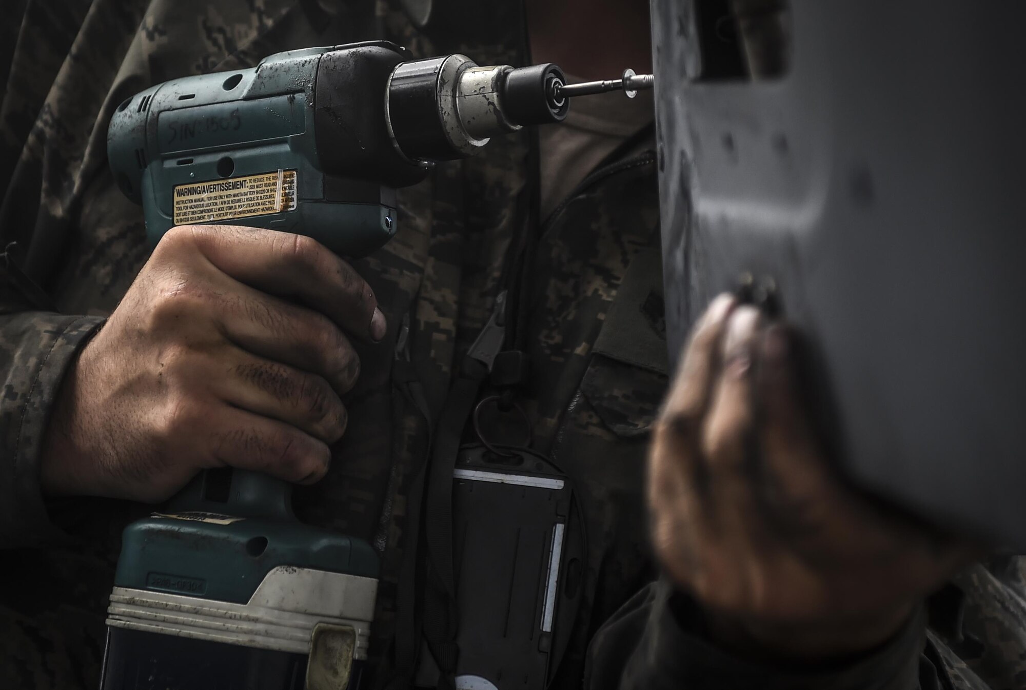 Senior Airman Braden Ferrell, 801st Special Operations Aircraft Maintenance Squadron crew chief, fastens an infrared deflector panel back on to a CV-22B Osprey during routine maintenance at Hurlburt Field, Fla., Oct. 27, 2015. Despite the after-effects of Hurricane Patricia, crew chiefs with the 801st SOAXMS continued performing maintenance to accomplish the mission. (U.S. Air Force photo by Senior Airman Christopher Callaway/Released)