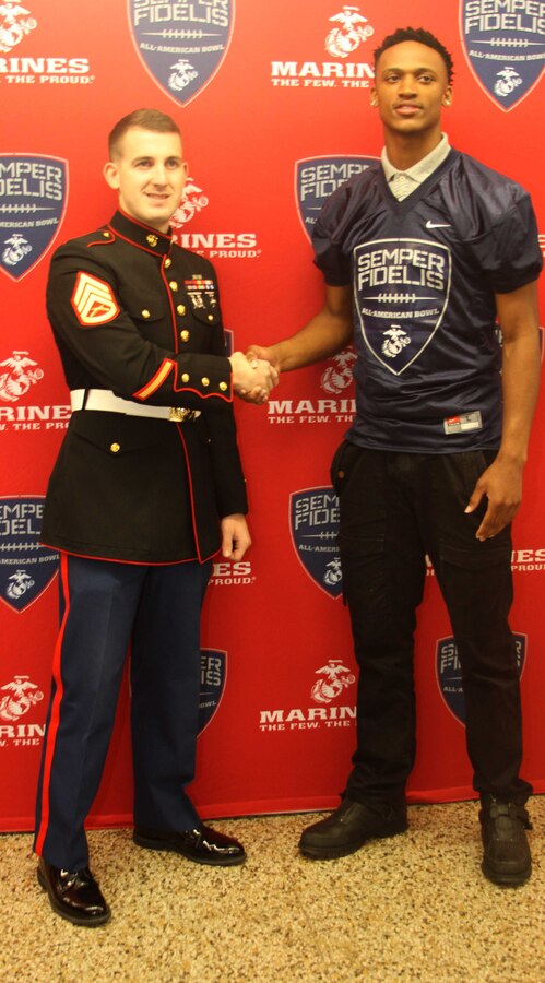 Diondre Overton, a wide receiver for the Page High School football team, shakes hands with U.S. Marine Corps Staff Sgt. Wesley M. Hughes, the staff noncommissioned officer in charge of Marine Corps Recruiting Sub-station Greensboro, during his Semper Fidelis All-American Bowl jersey presentation at Page High School in Greensboro, North Carolina, Oct. 22, 2015. Overton was selected to play in the bowl for his skill as a wide receiver, his academics and his leadership ability.  The Semper Fidelis All-American Bowl allows the Marine Corps to purposefully engage with well-rounded student athletes and share leadership lessons that will enable future success. It will be played on Jan. 3, 2016, in Carson, California, and will be broadcast on Fox Sports 1. (U.S. Marine Corps photo by Sgt. Dwight A. Henderson/Released) 