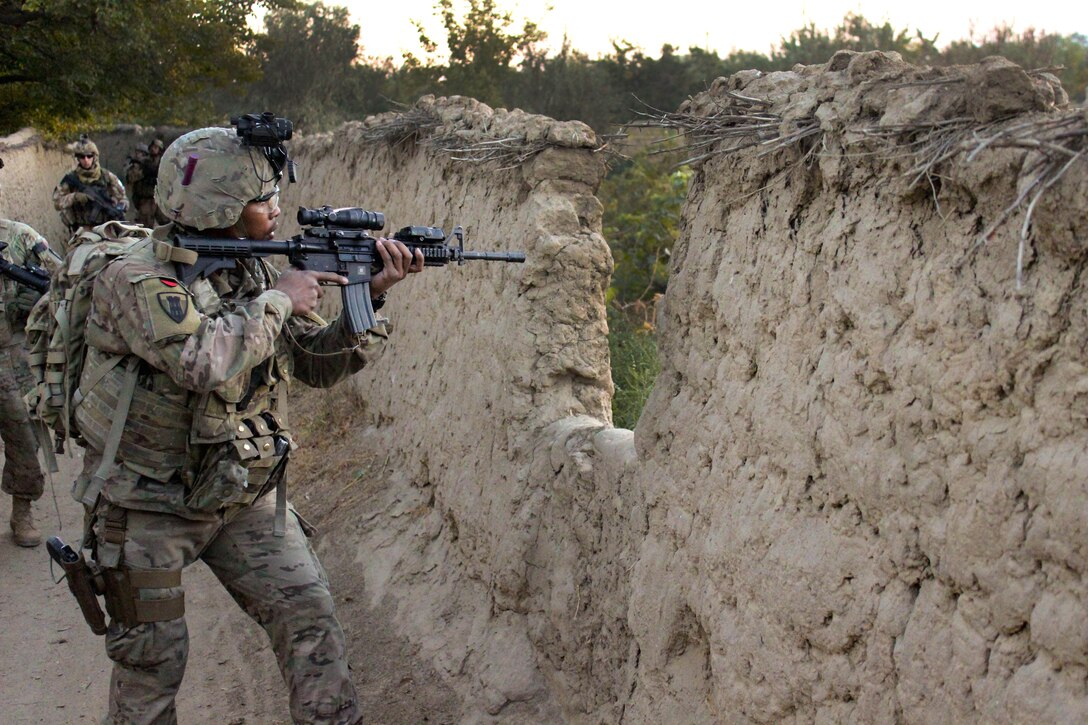 A U.S. soldier provides security and scans the area through a mud wall as Czech and Afghan soldiers conduct a mission through a village in Parwan province, Afghanistan, Oct. 20, 2015. U.S. Army photo by Sgt. 1st Class David Wheeler