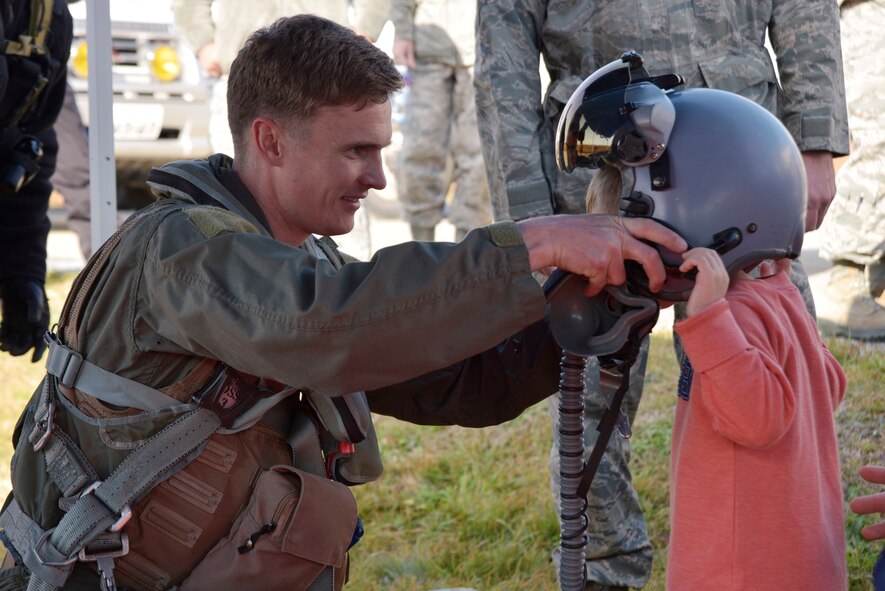 U.S. Air Force Staff Sgt. Jason Allchin, 35th Operations Support Squadron survival, evasion, resistance and escape specialist, fits a fighter pilot helmet on an attendee of Range Day hosted by the 35th Operations Group at at Draughon Range outside Misawa Air Base, Japan, Oct. 30, 2015. Families, including children, were invited to learn and experience the 35 OG mission. (U.S. Air Force photo by Senior Airman Jose L. Hernandez-Domitilo/Released)