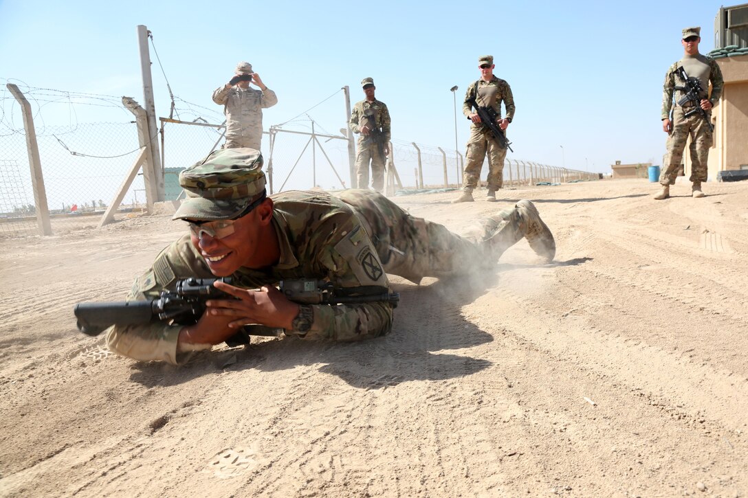 A U.S. soldier smiles as he demonstrates how to high crawl with weapons to Iraqi army engineers at Besmaya Range Complex, Iraq, Oct. 25, 2015. The high crawl allows a soldier to move faster than the low crawl while still allowing for a low silhouette. The U.S. soldier is assigned to the 10th Mountain Division's Company C, 1st Battalion, 32nd Infantry Regiment, 1st Brigade Combat Team. U.S. Army photo by Cpl. Nelson Rodriguez
