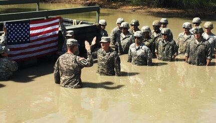 Sgt. Luis Suarez, a student enrolled in the Wheeled Vehicle Recovery Course at Regional Training Site Maintenance-Fort Hood, Texas, takes the oath of reenlistment administered by his company commander Capt. Andrew Schwilk, E Company 227th Aviation Regiment, at the school’s mire pit April, 2015. 
Suarez said, he reenlisted in the pit to give Schwilk, who attained the Additional Skills Identifier earlier in his career, an opportunity to go back to his muddy roots and to motivate other Wheeled vehicle mechanics to earn the ASI. 