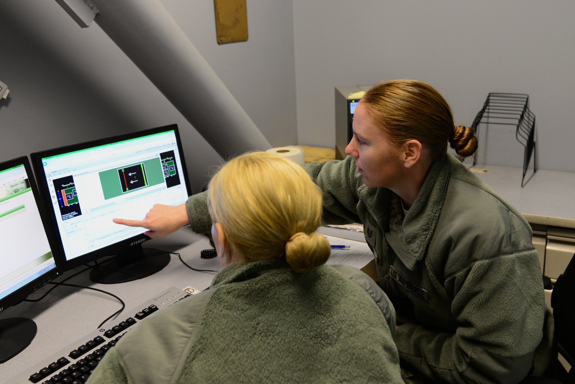 U.S. Air Force Tech. Sgt. Rebecca Morin, the 354th Logistics Readiness Squadron (LRS) noncommissioned officer in charge (NCOIC) of air terminal operations, explains the loading plan to Staff Sgt. Rebecca Bartlett, the 354th LRS NCOIC of passenger deployments, Oct. 28, 2015, at Eielson Air Force Base, Alaska. They discuss the load plan for a fuel tank to be installed on an aircraft. (U.S. Air Force photo by Airman 1st Class Cassandra Whitman/Released)