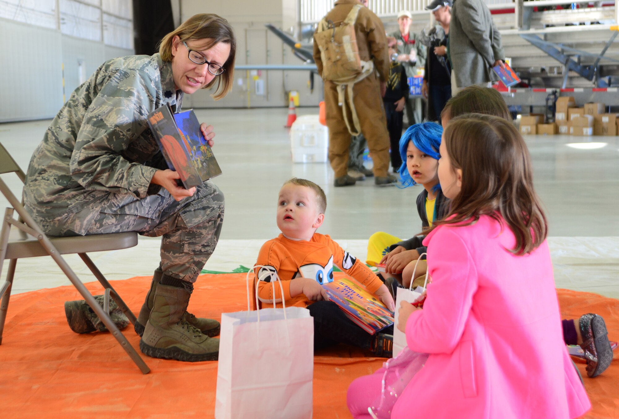 Lt. Col. Mackenzie Shultz, 432nd Aircraft Maintenance Squadron commander, reads to a group of children during the 2015 children's halloween party Oct. 30, 2015, at Creech Air Force Base, Nevada. The event gave children the opportunity for a day of fun with their Air Force parents and other families. (U.S. Air Force photo by Airman 1st Class Christian Clausen/Released)