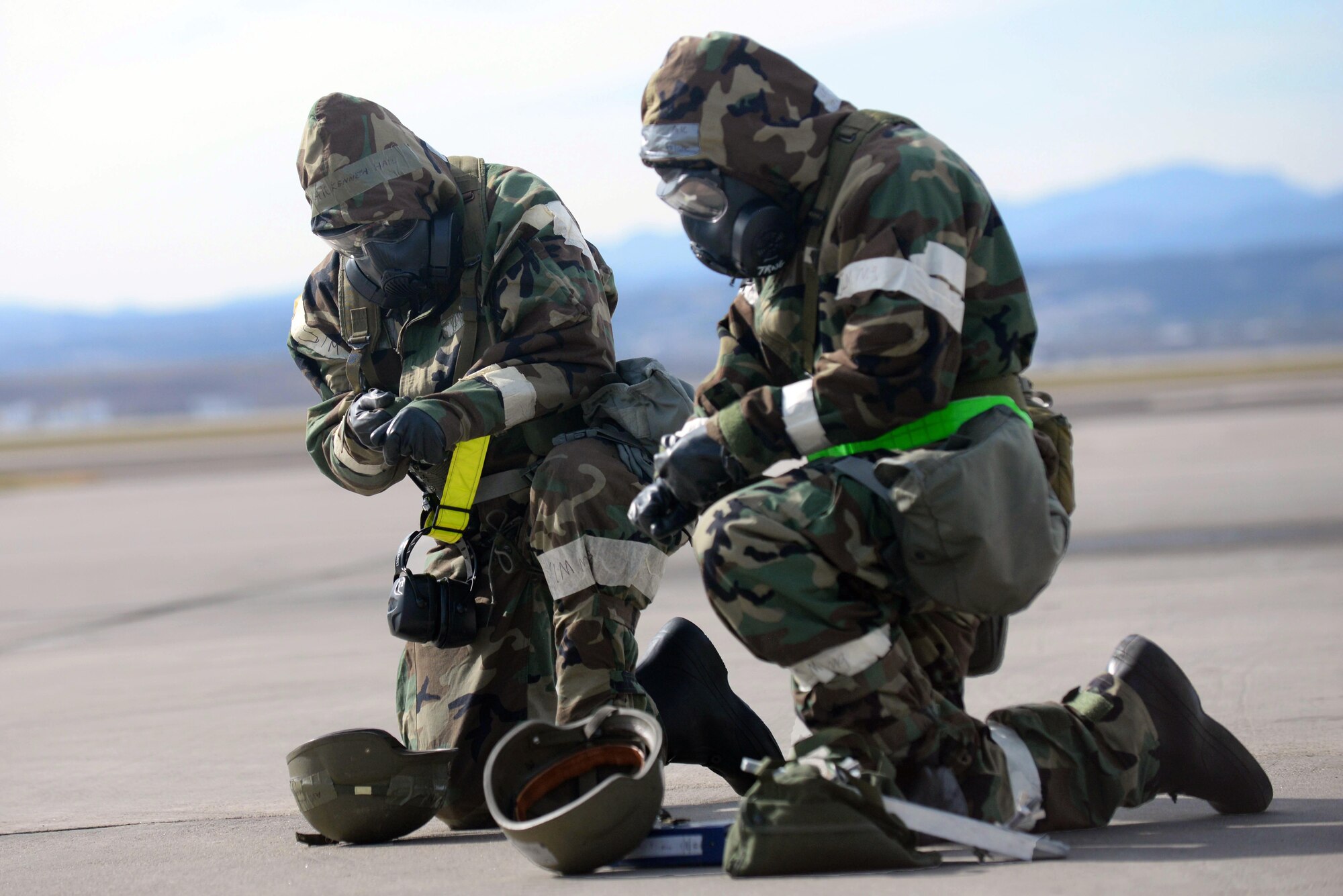 Airmen 1st Class Kenneth Hall, left, and Blake Guiterrez, right, 28th Aircraft Maintenance Squadron weapons load crew members, don mission oriented protective posture gear during a base operational readiness exercise at Ellsworth Air Force Base, S.D., Oct. 20, 2015. MOPP gear is used to protect Airmen in a toxic environment and consists of chemical and biological warfare jacket and pants, protective rubber boots and gloves, a helmet and a gas mask. (U.S. Air Force photo by Senior Airman Rebecca Imwalle/Released)
