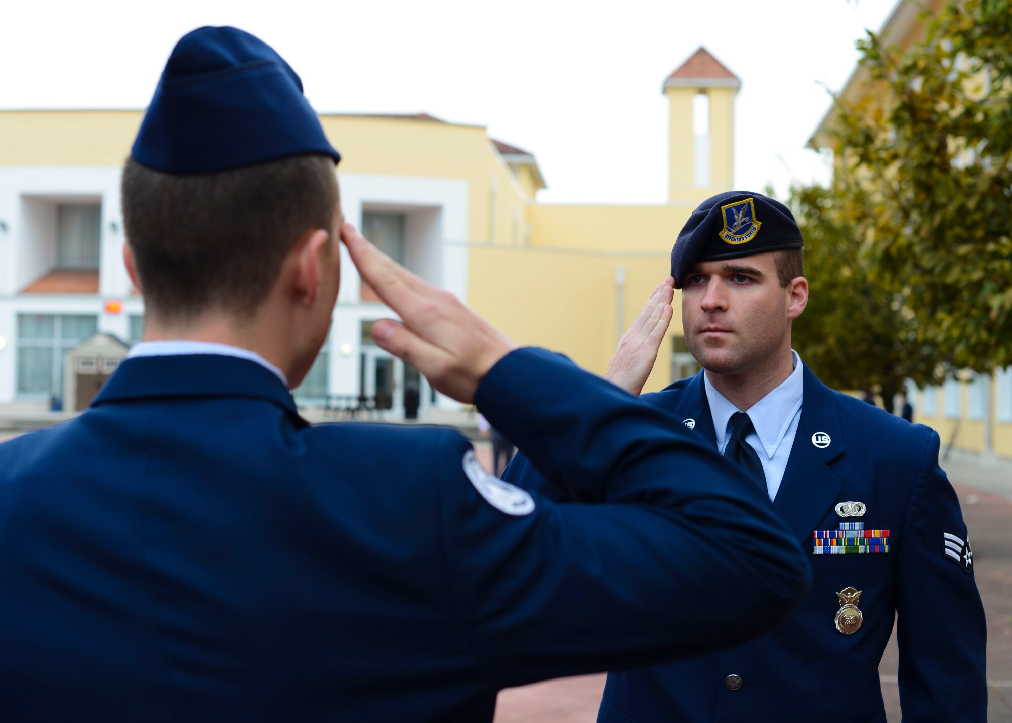 U.S. Air Force Senior Airman Revik Walker, 31st Security Forces Squadron desk sergeant, salutes an Aviano High School JROTC cadet after critiquing a marching routine during Corps Day, Oct. 28, 2016, at Aviano Air Base, Italy. Walker and other volunteers judged drill, color guard, dress and appearance and flag detail to prepare the cadets for a Nov. 14 drill competition. (U.S. Air Force photo by Senior Airman Austin Harvill/Released)