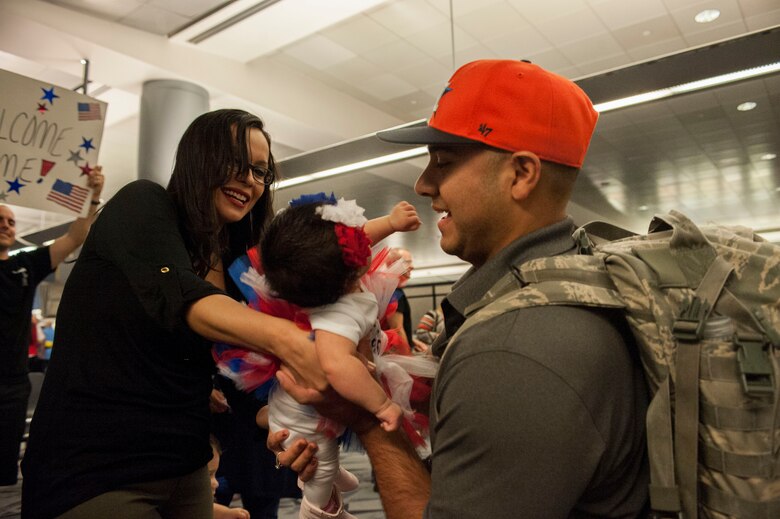 Tech. Sgt. Alberto Galvan, 926th Security Forces Squadron member, embraces his daughter for the first time after returning from a deployment at McCarran International Airport in Las Vegas, Oct. 22, 2015. While deployed, Galvan was able to video chat with his wife while she gave birth to their daughter, who is one month old. (U.S. Air Force photo by Airman 1st Class Jake Carter)