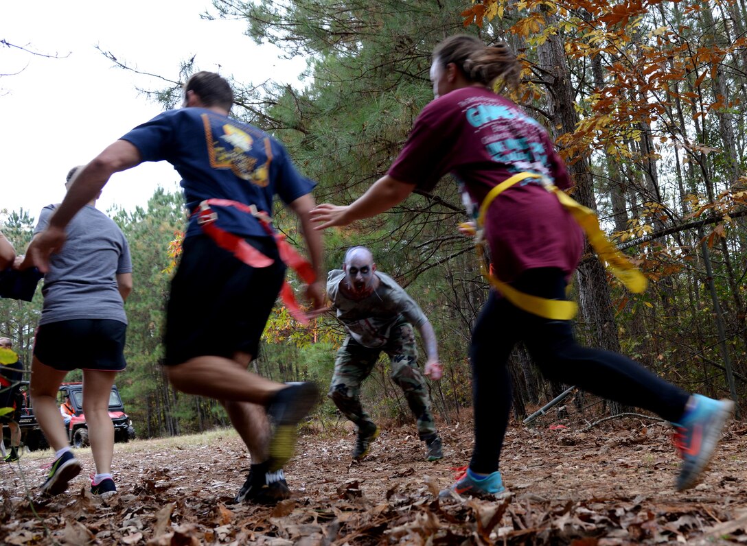 A group of Columbus Air Force members run from a zombie during the third annual Zombie Run 5k Oct. 31 at Columbus AFB, Mississippi. The participants had to protect three flags hanging from their waist as they went through obstacles and past the undead. (U.S. Air Force Photo/Airman 1st Class John Day)