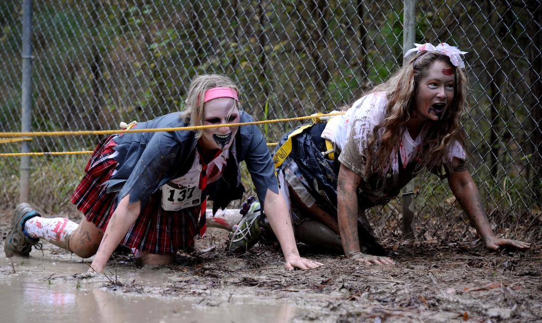 Two runners dressed as zombies do a low crawl through an obstacle course during the third annual Zombie Run 5k Oct. 31 at Columbus AFB, Mississippi. Several of the obstacles runners had to go through included a wall climb, crawling through tubes and jumping over tires. (U.S. Air Force Photo/Airman 1st Class John Day)