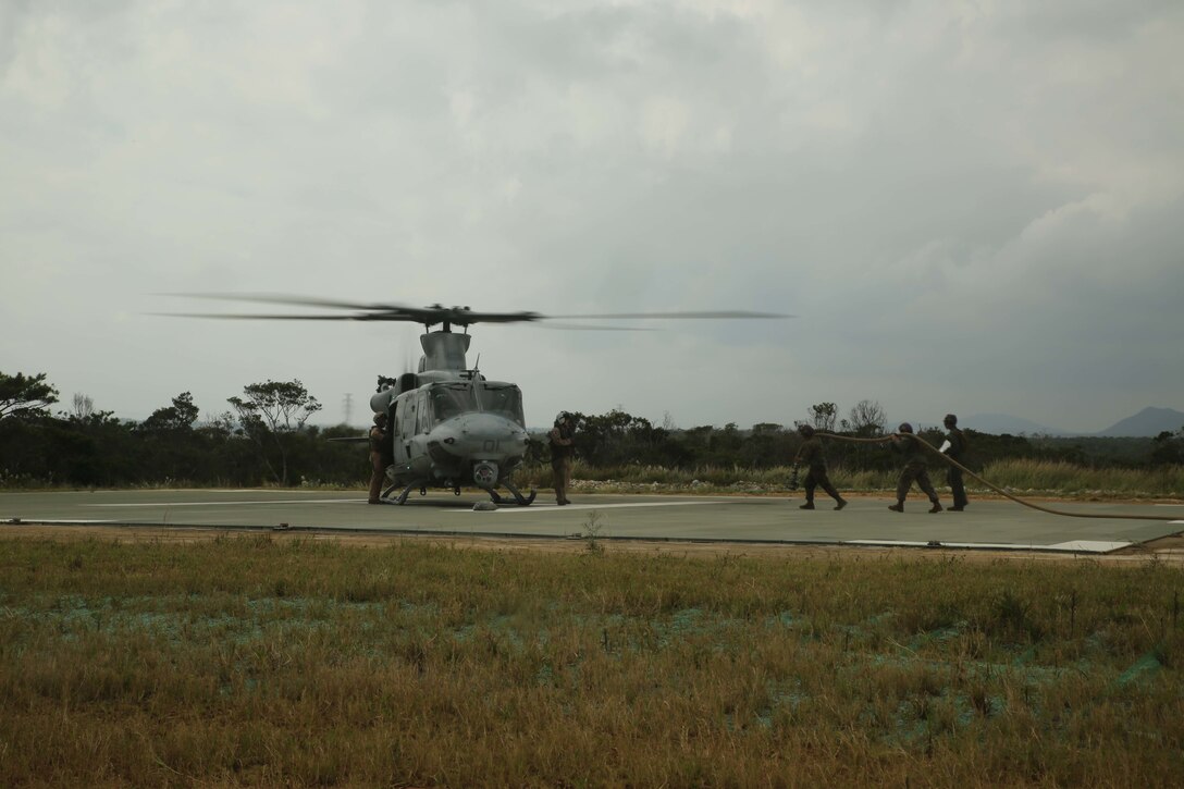 Marines with Marine Wing Support Squadron 172 bring a fuel hose to pilots of a UH-1Y Huey during Blue Chromite, in Landing Zone Phoenix, Camp Schwab, Okinawa, Japan, Oct. 31, 2015. Marines with MWSS-172, which falls under Marine Air Group 36, 1st Marine Aircraft Wing, III Marine Expeditionary Force, executed a forward armament and refueling point to provide aircraft also supporting Blue Chromite with fuel to continue defending the ground element of the Marine Air Ground Task Force. Blue Chromite is a large-scale amphibious exercise that draws primarily from III MEF training resources on Okinawa. The location of the training allows participating units to maintain a forward-deployed posture and eliminates the cost of traveling to train. (U.S. Marine Corps Photo by Cpl. Natalie A. Dillon/Released)