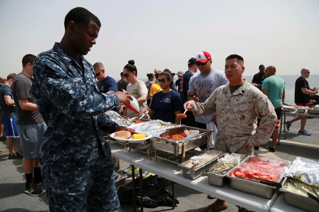 GULF OF ADEN (Aug. 29, 2015) U.S. Marines and Sailors from the 15th Marine Expeditionary Unit and Essex Amphibious Ready Group fill their plates with food at a steel beach picnic aboard the amphibious transport dock ship USS Anchorage (LPD 23). Elements of the 15th MEU are embarked aboard the Anchorage, which is part of the ESX ARG, and is deployed in support of maritime security operations and theater security cooperation efforts in the U.S. 5th Fleet area of operations. (U.S. Marine Corps photo by Sgt. Steve H. Lopez/Released)