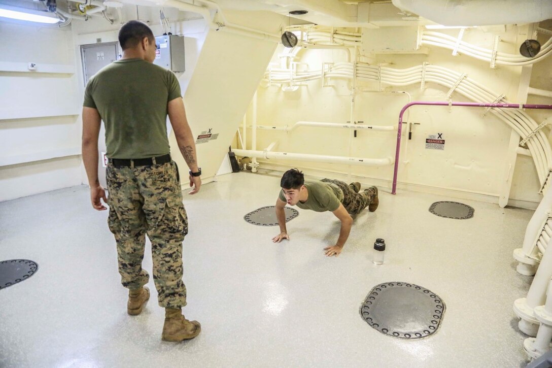 GULF OF ADEN (Aug. 28, 2015) U.S. Marine Cpl. Oscar Sotomeza, left, supervises Sgt. Christian Gallegos as he does burpees during a Marine Corps martial arts program green belt course aboard the amphibious transport dock ship USS Anchorage (LPD 23). Sotomeza is a rifleman and Gallegos is an intelligence specialist both assigned to Headquarters and Service Company, Battalion Landing Team 3rd Battalion, 1st Marine Regiment, 15th Marine Expeditionary Unit.  The 15th MEU is embarked on the Essex Amphibious Ready Group and deployed in support of maritime security operations and theater security cooperation efforts in the U.S. 5th Fleet area of operations. (U.S. Marine Corps photo by Sgt. Steve H. Lopez/Released)