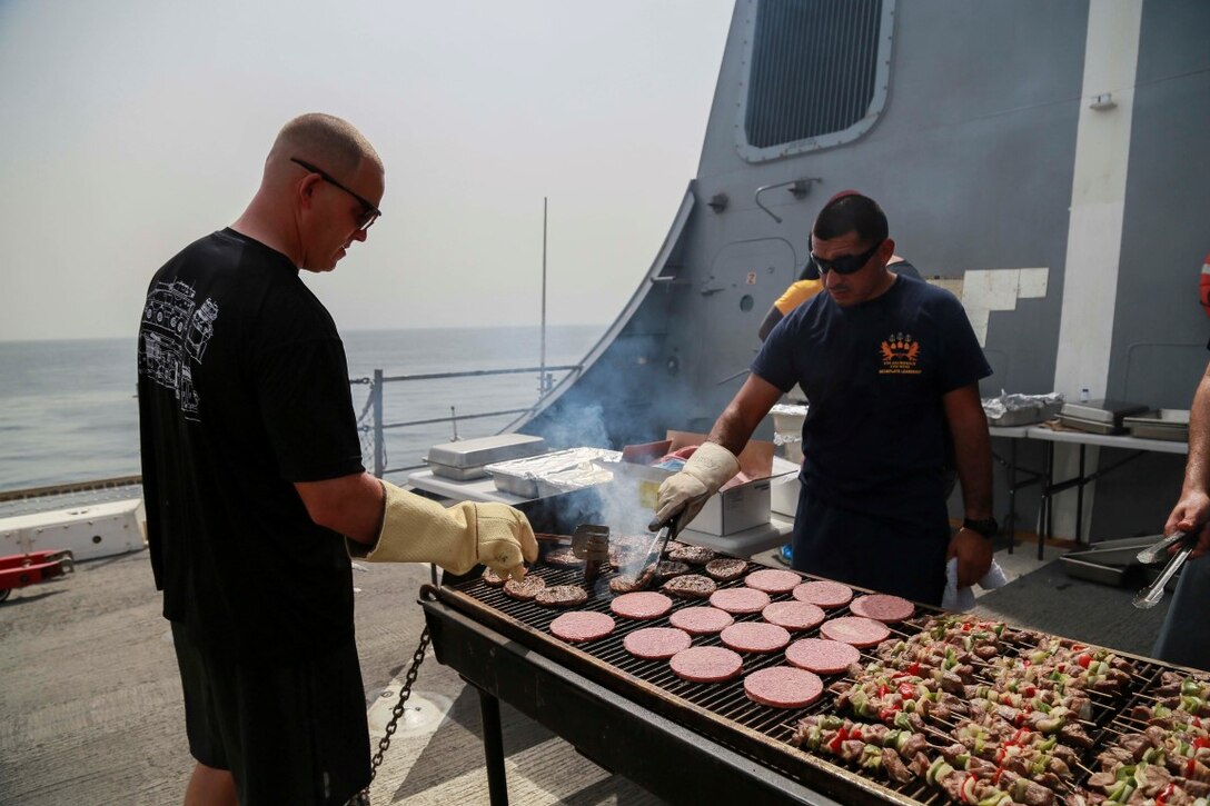 GULF OF ADEN (Aug. 29, 2015) U.S. Marine Master Sgt. Brian Stirrat, left, cooks on the grill during a steel beach picnic aboard the amphibious transport dock ship USS Anchorage (LPD 23). Stirrat is the Operations Chief with Delta Company, Light Armored Reconnaissance Detachment, Battalion Landing Team 3rd Battalion, 1st Marine Regiment, 15th Marine Expeditionary Unit. Elements of the 15th MEU are embarked aboard the Anchorage, which is part of the Essex Amphibious Ready Group, and is deployed in support of maritime security operations and theater security cooperation efforts in the U.S. 5th Fleet area of operations. (U.S. Marine Corps photo by Sgt. Steve H. Lopez/Released)