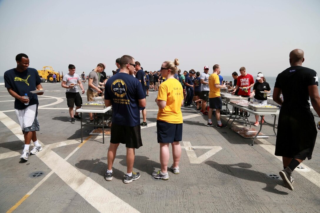 GULF OF ADEN (Aug. 29, 2015) U.S. Marines and Sailors from the 15th Marine Expeditionary Unit and Essex Amphibious Ready Group fill their plates with food at a steel beach picnic aboard the amphibious transport dock ship USS Anchorage (LPD 23). Elements of the 15th MEU are embarked aboard the Anchorage, which is part of the ESX ARG, and is deployed in support of maritime security operations and theater security cooperation efforts in the U.S. 5th Fleet area of operations. (U.S. Marine Corps photo by Sgt. Steve H. Lopez/Released)