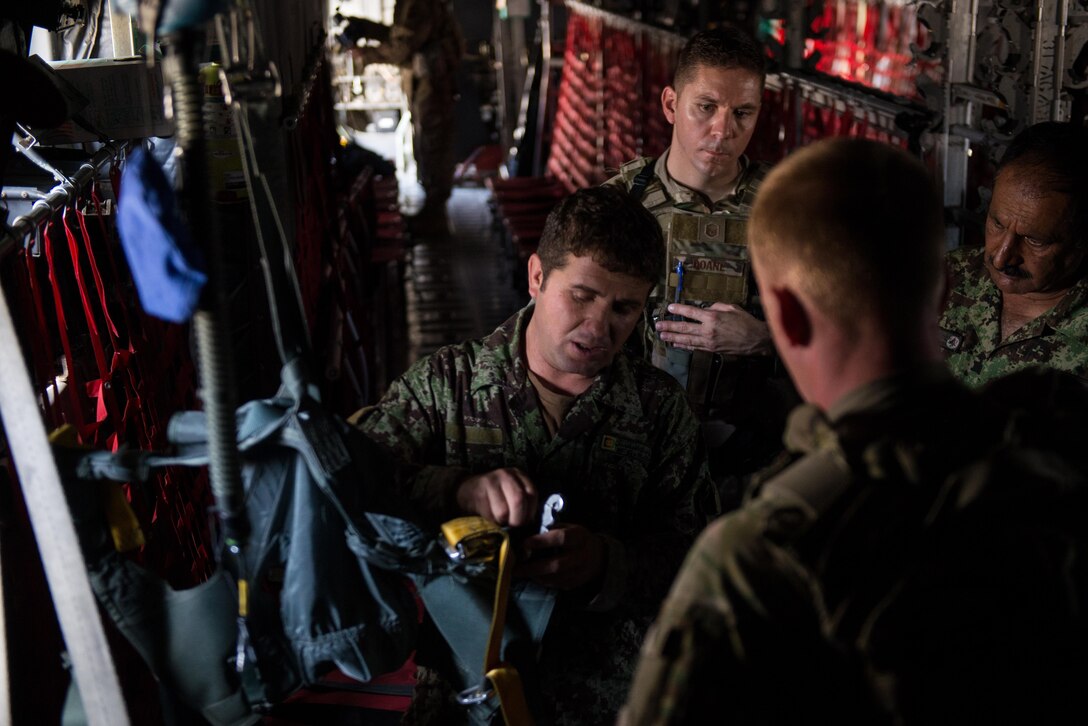 An Afghan airman demonstrates his aircrew flight equipment knowledge to U.S. Airmen from the 455th Air Expeditionary Wing and Train, Advice, Assist Command-Air aboard an Afghan C-130H Hercules at Hamid Karzai International Airport, Kabul, Afghanistan, Aug. 29, 2015. Airmen with the 455th AEW visited Forward Operating Base Oqab and Hamid Karzai International Airport to share their aircrew flight equipment knowledge with their Afghan counterparts and also assist TAAC-Air with keeping Coalition AFE equipment current. (U.S. Air Force photo by Tech. Sgt. Joseph Swafford/Released) 