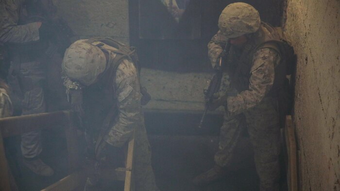 Marines with Alpha Fleet Antiterrorism Security Team Company move down a flight of stairs after utilizing a flash bang at a shoot house aboard the Northwest Annex during Advanced Urban Combat Training Aug. 28. The training allowed the Marines to use live rounds and flash bang grenades throughout the training to test them under a stressful situation.