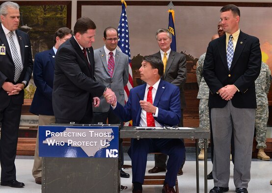 Individual Mobilization Augmentee and North Carolina legislator, Col. Chris Whitmire (left), shakes hands with Governor Pat McCrory (right, seated), governor of the state, during the signing of House Bill 371, a counter-terrorism law. (Courtesy photo)