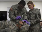 New York Army National Guard 1st Lt. Christine Kalafut from the 369th Sustainment Brigade oversees Spc. Godfrey Zulueta inserting a nasopharyngeal airway in Sgt. Henry Quindara during a Combat Lifesaver course at Fort Drum, New York, Aug. 18, 2015. 