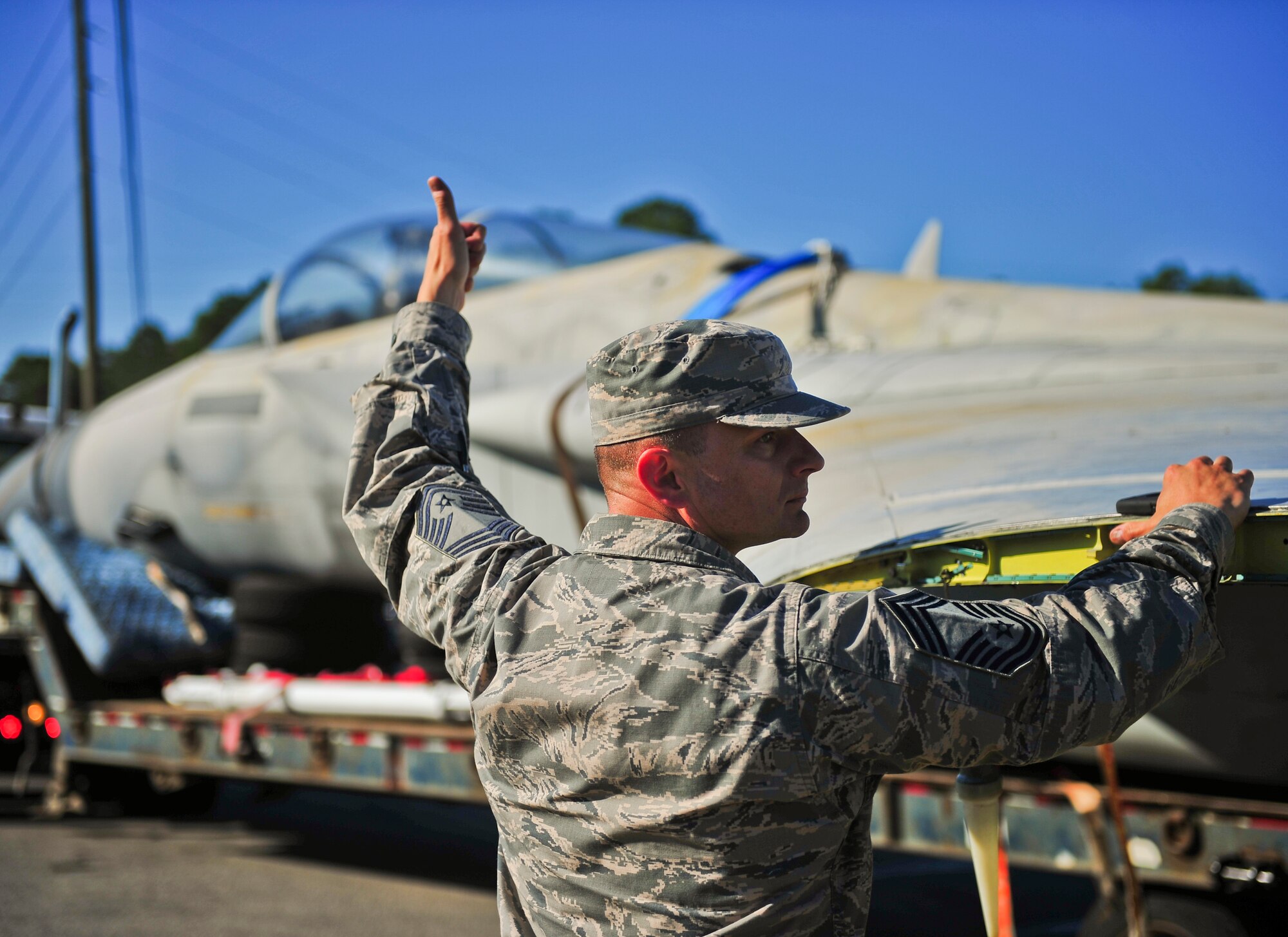 Chief Master Sgt. Gregory Fenger, 325th Maintenance Group chief, assists a flatbed semi-truck driver back up while transporting an F-15C Eagle 30 Aug. The F-15C was used as a Ground Instructional Training Aircraft for Airmen training to become F-15C crew chiefs when they were assigned to Tyndall. (U.S. Air Force photo by Airman 1st Class Dustin Mullen/Released)